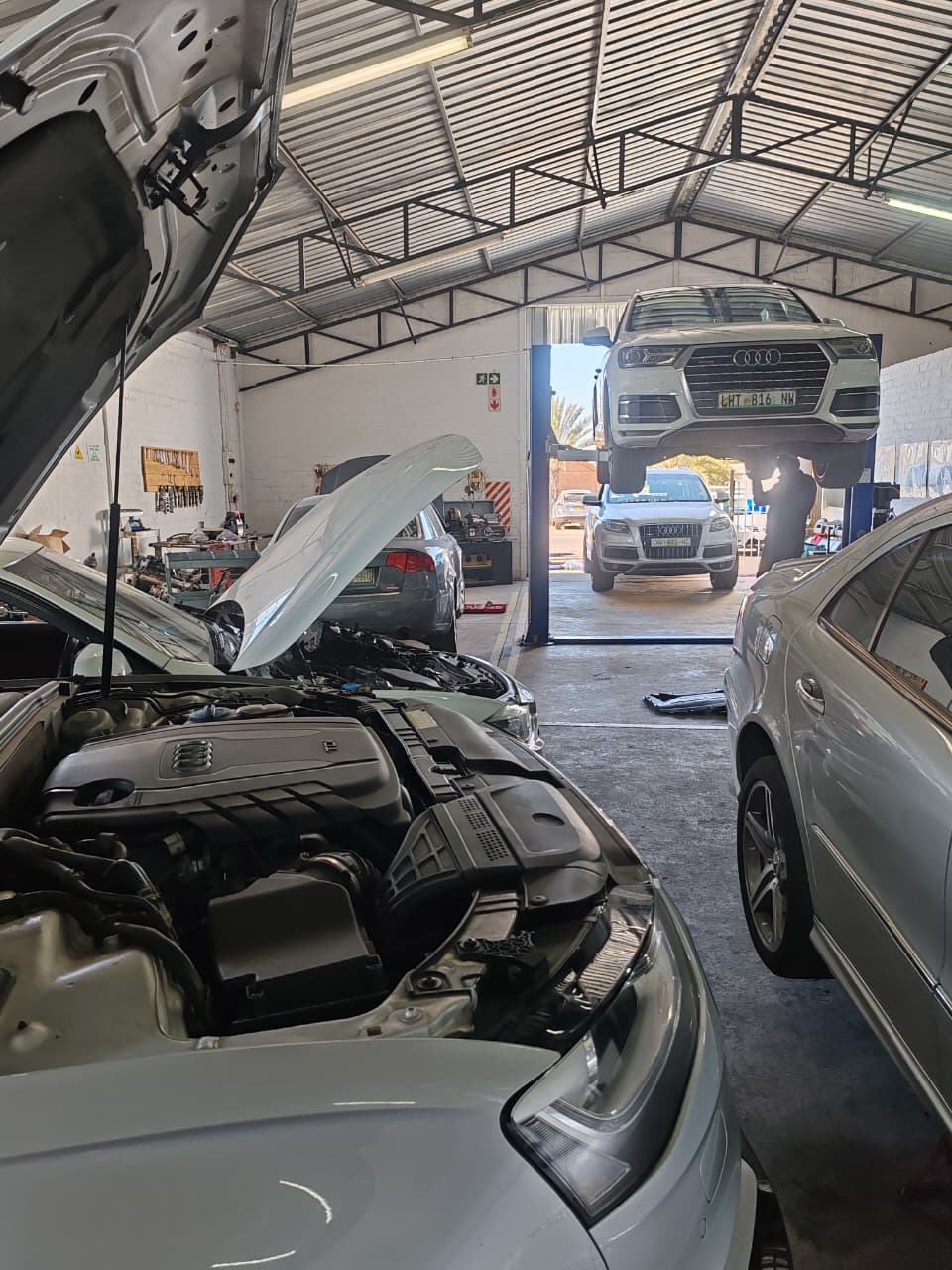 Audi Q7 on the lift beside an Audi engine bay under service